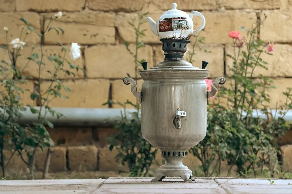 Rustic samovar with teapot in an Azerbaijan garden, surrounded by flowers.
